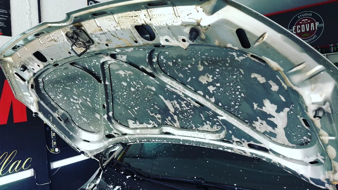 Capô aberto com pintura refletindo o teto da oficina